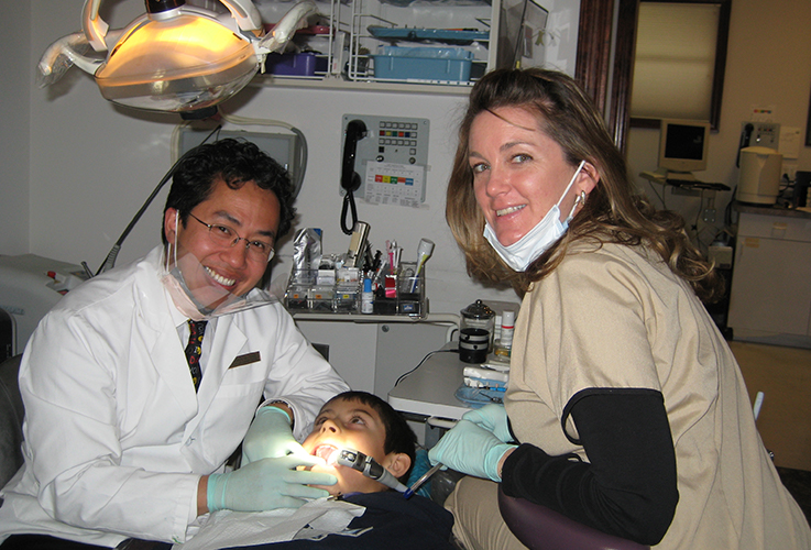Dr. Tong and team member working with child in dental chair