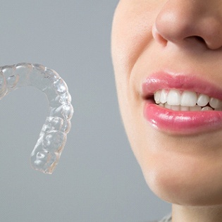 A woman holding an Invisalign aligner