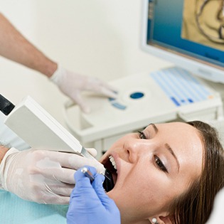 A dentist uses a handheld device and CEREC technology to produce a high-resolution image of a patient’s tooth to prepare a same-day crown