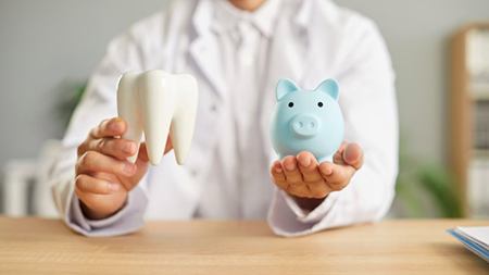 a dentist holding a tooth and a piggy bank