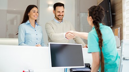a couple of patients speaking with a front desk member