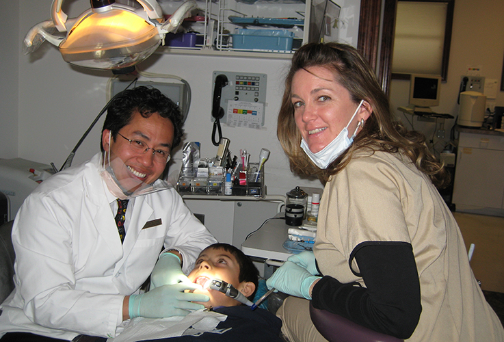 Dr. Tong and team member working with child in dental chair