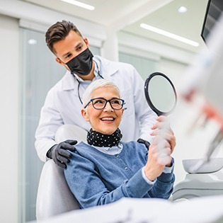 Woman smiling at reflection in mirror with dentist