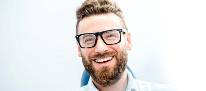 A man wearing glasses and smiling after receiving a dental bridge in Tappan