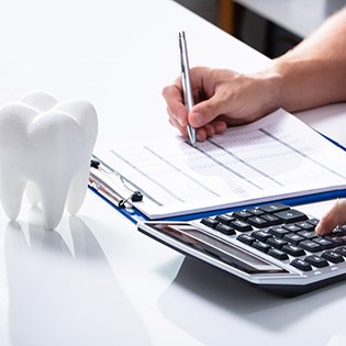 Tooth on table, person using a calculator