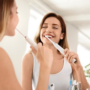 Woman brushing her teeth with an electric toothbrush