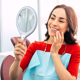 A smiling woman pointing to her mouth