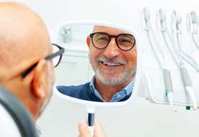 Patient with black glasses smiling at reflection