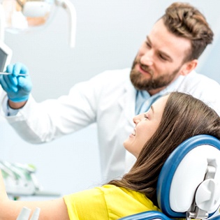 A dentist discussing an image on a screen with a female patient