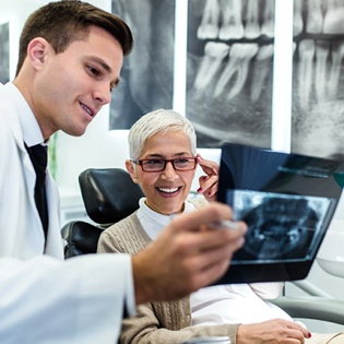 An older woman reviewing X-rays with her dentist