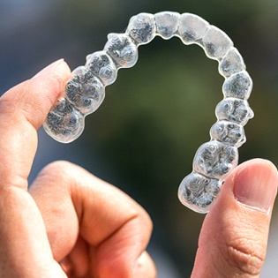Someone holding up a clear aligner tray