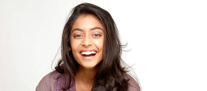 A young woman with long, dark hair smiling in preparation of seeing her sedation dentist in Tappan