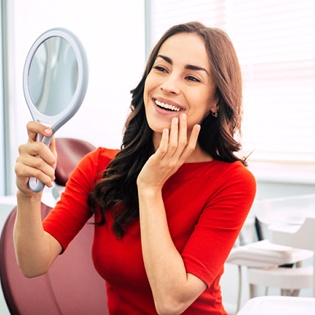 A woman looking at her smile in the mirror