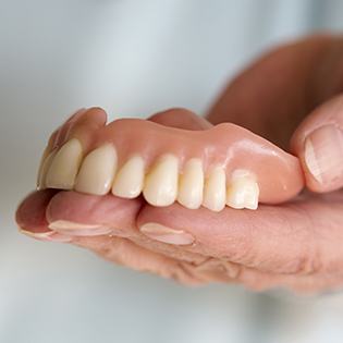 Hand holding a full denture