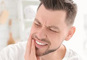 Man grimacing and holding jaw