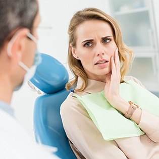 Woman in dental chair holding cheek