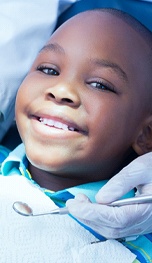 A young boy smiles while the dentist prepares to perform a regular checkup and cleaning in Tappan