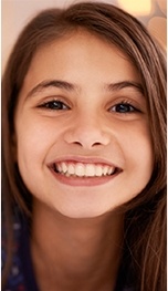 A young girl with brown hair smiles after receiving a tooth-colored filling in Tappan