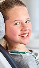 A young girl seated in the dentist’s chair and smiling in preparation to receive sedation dentistry in Tappan