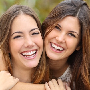 Two young women smiling and hugging