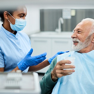 Dentist talking to smiling patient sitting in treatment chair