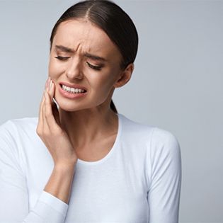 A woman holding her cheek in pain