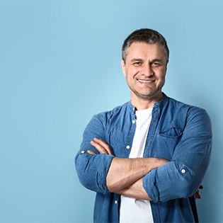 An older gentleman smiling with his arms crossed