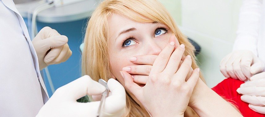 Woman in dental chair covering mouth