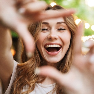 Smiling woman framing face with fingers