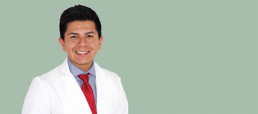 Dr. Muñoz sonriendo a la cámara con fondo azul