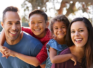 Familia sonriendo abrazándose mientras está afuera