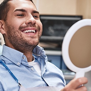 Hombre sonriendo en el sillón dental en el espejo