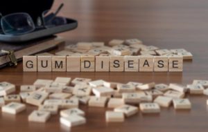 "gum disease" in Tappan written out in Scrabble tiles on a table