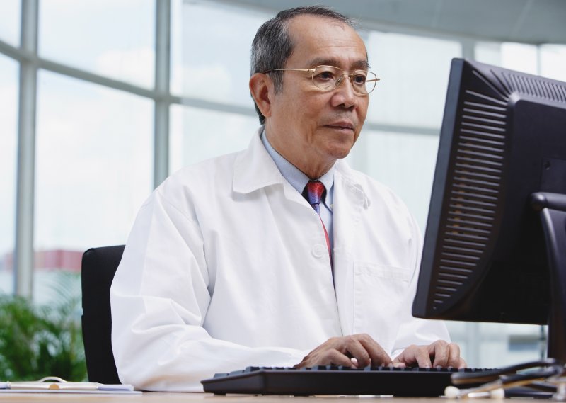 an emergency dentist in Tappan sitting in front of a computer preparing to speak to a patient