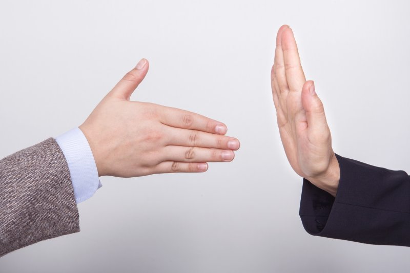 a person trying to shake hands while another puts a hand up to stop them