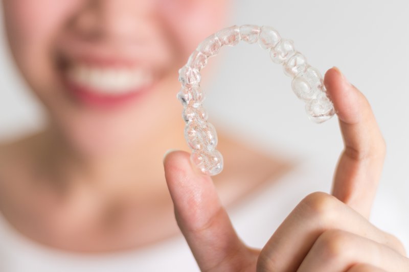 an up-close view of a person holding an Invisalign aligner in their left hand