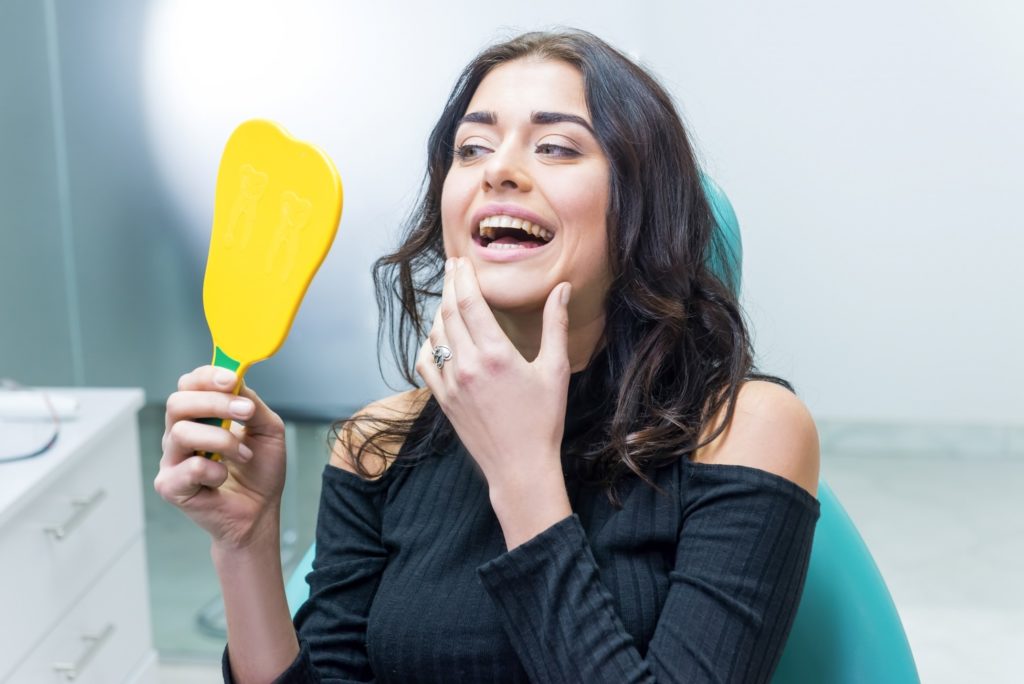 Woman looking at her teeth in dentist's mirror