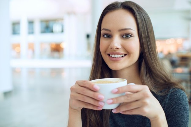Woman smiling and drinking coffee.