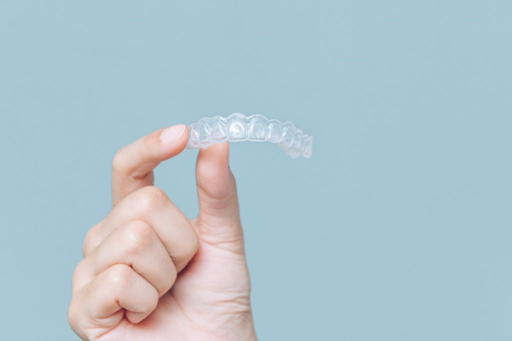 Invisalign clear aligner in hand.