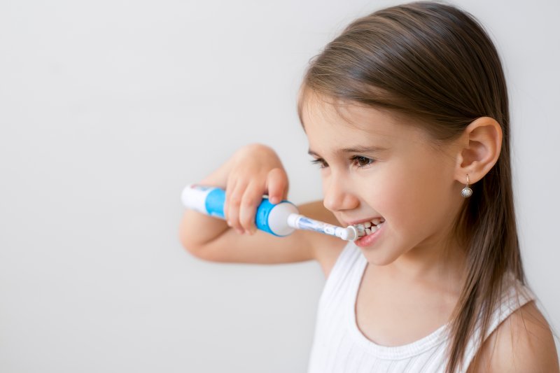 girl using an electric toothbrush