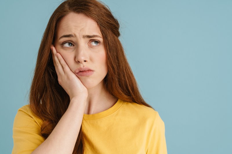 A woman holding her cheek due to a toothache