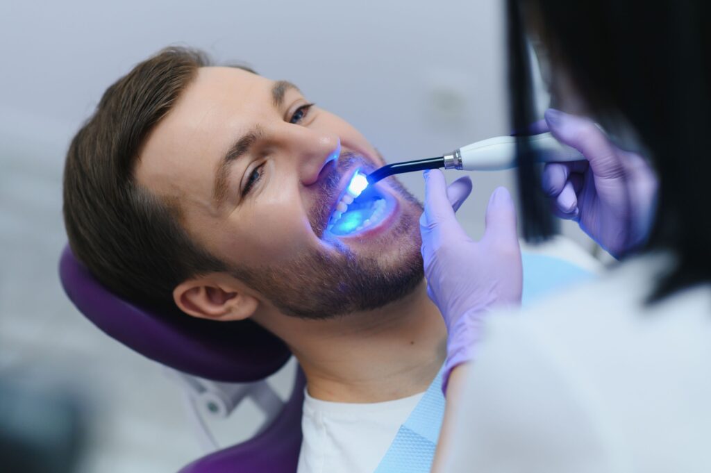 Man in dental chair having dental bonding hardened with UV light