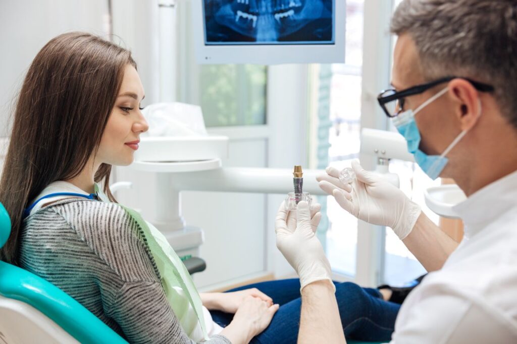 A woman looking at a dental implant model with her dentist